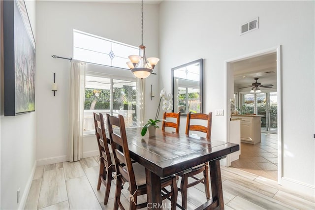 dining area with ceiling fan with notable chandelier and a towering ceiling