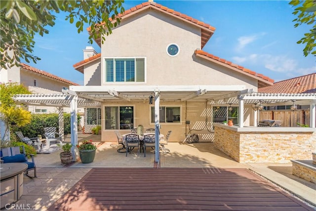 back of house featuring a patio, a deck, exterior bar, and a pergola