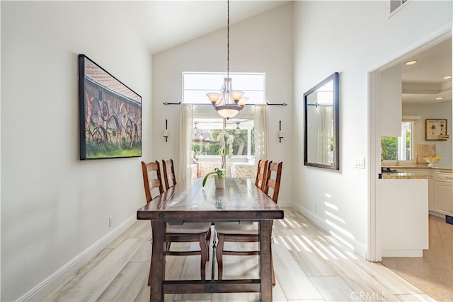 dining area with high vaulted ceiling, light tile patterned flooring, and an inviting chandelier