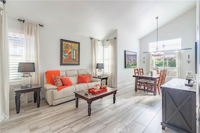 living room featuring an inviting chandelier, lofted ceiling, and plenty of natural light