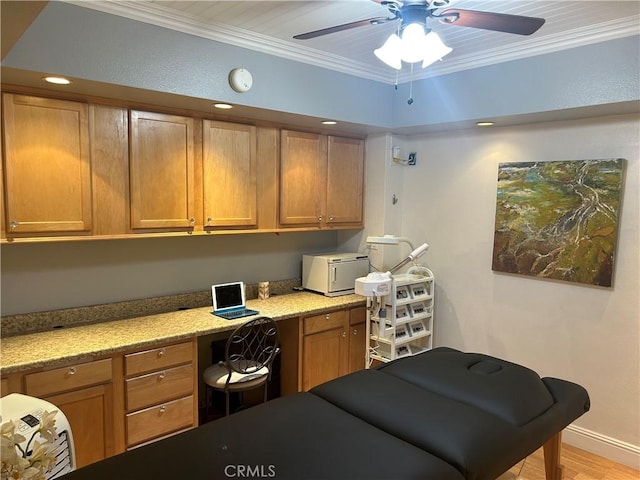 office space with built in desk, ornamental molding, ceiling fan, and light hardwood / wood-style flooring