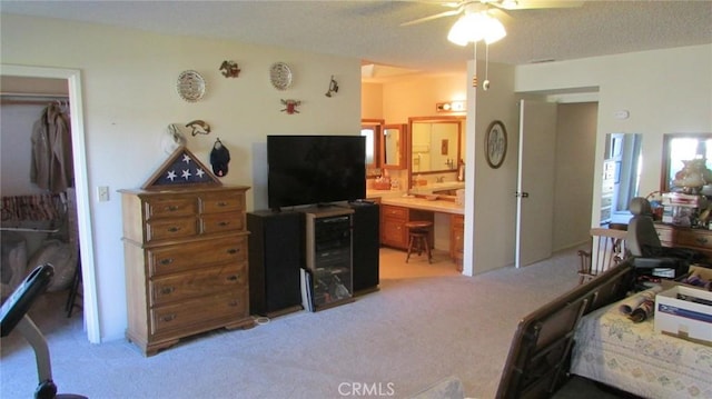 carpeted bedroom with ceiling fan, ensuite bathroom, a closet, and a textured ceiling