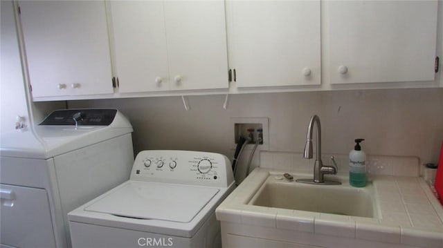 laundry area with separate washer and dryer, cabinets, and sink