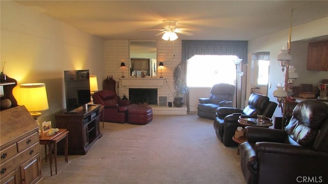 living room with a large fireplace, ceiling fan, and light colored carpet