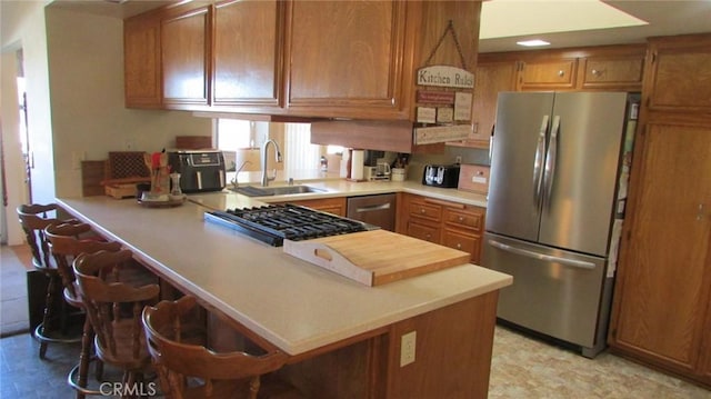 kitchen with sink, stainless steel appliances, a breakfast bar area, and kitchen peninsula