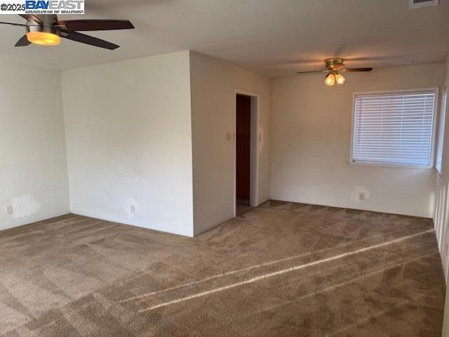 empty room featuring carpet floors and ceiling fan