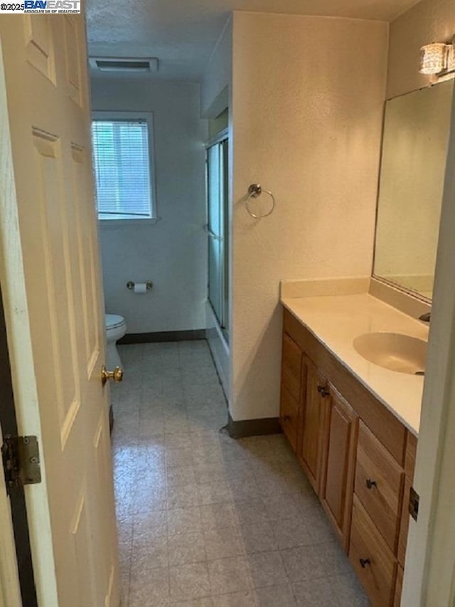 bathroom with toilet, walk in shower, and vanity