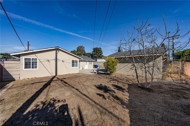 rear view of property with a fenced backyard and stucco siding