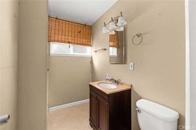 half bath with toilet, vanity, baseboards, and tile patterned floors