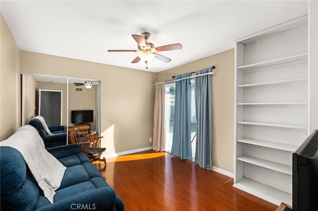 living room featuring ceiling fan, baseboards, and wood finished floors