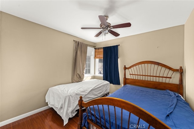 bedroom with ceiling fan, baseboards, and wood finished floors