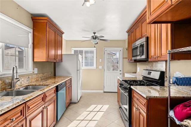 kitchen with brown cabinets, appliances with stainless steel finishes, a sink, and a healthy amount of sunlight