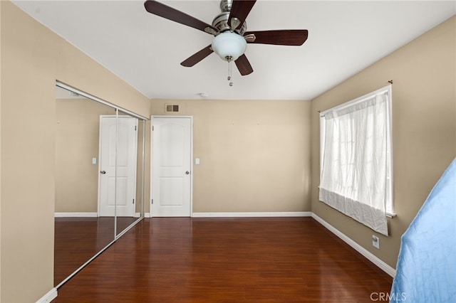 unfurnished bedroom with ceiling fan, wood finished floors, visible vents, baseboards, and a closet