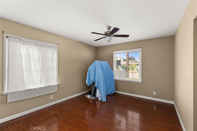 empty room featuring a ceiling fan, baseboards, and wood finished floors