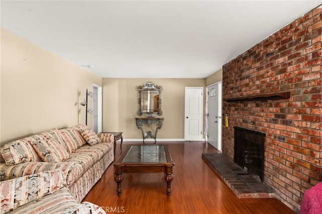 living area featuring a brick fireplace, baseboards, and wood finished floors