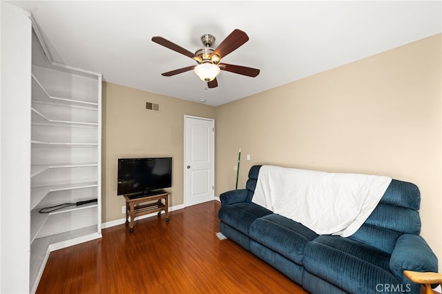 living area with a ceiling fan, wood finished floors, visible vents, and baseboards