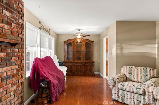 living area with wood finished floors, a ceiling fan, and baseboards