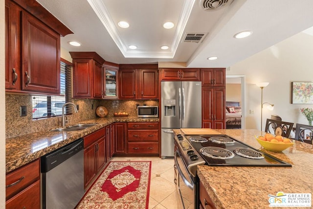 kitchen with sink, light tile patterned flooring, ornamental molding, a tray ceiling, and appliances with stainless steel finishes