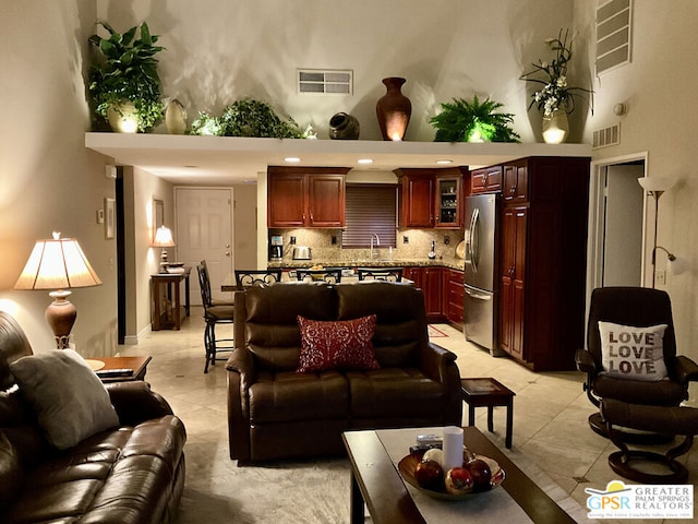 living room with a towering ceiling and light tile patterned flooring