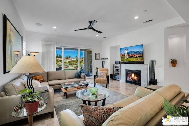 living room featuring a tile fireplace, ceiling fan, and light tile patterned floors