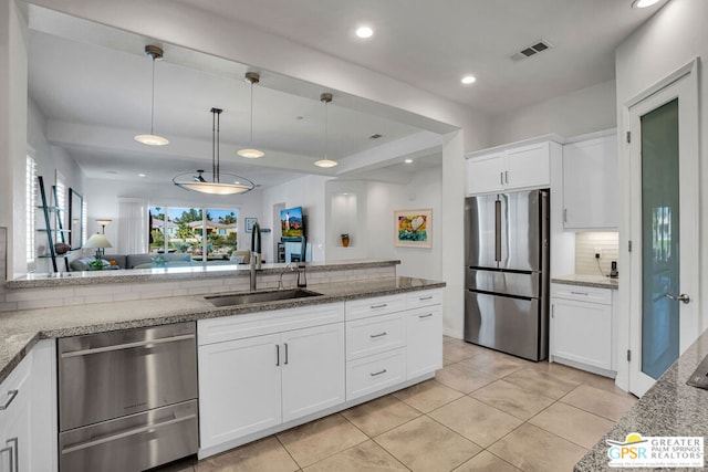 kitchen with appliances with stainless steel finishes, pendant lighting, white cabinetry, and decorative backsplash