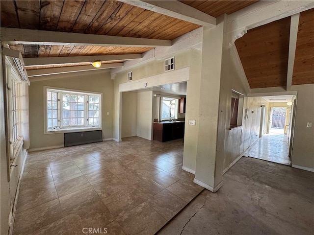 empty room with a healthy amount of sunlight, wooden ceiling, and vaulted ceiling with beams