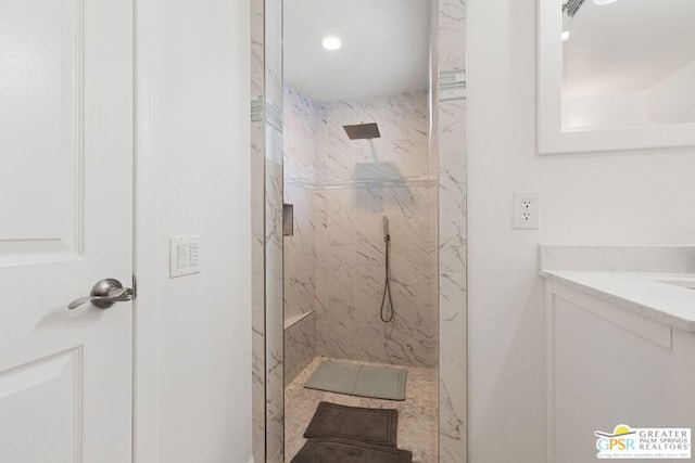 bathroom with tiled shower and vanity