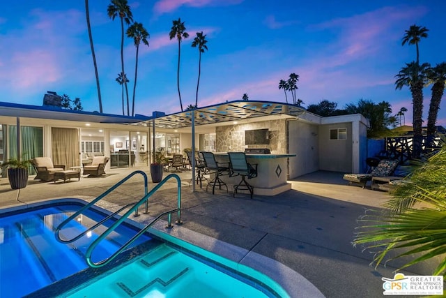 pool at dusk featuring a bar and a patio