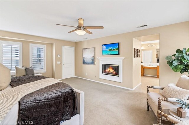 carpeted bedroom featuring ceiling fan and ensuite bathroom