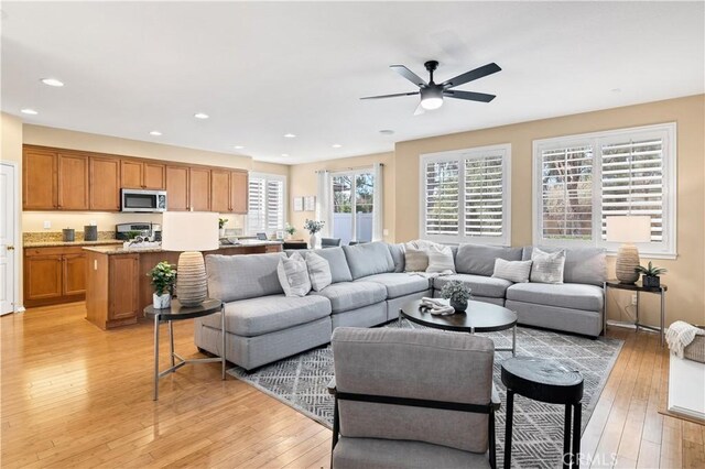 living room featuring ceiling fan, a wealth of natural light, and light wood-type flooring