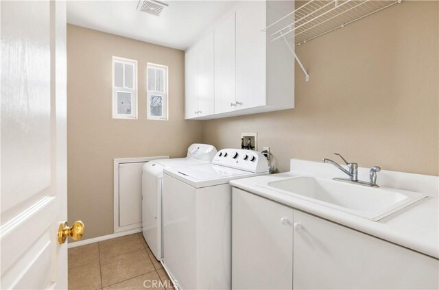 clothes washing area featuring cabinets, sink, light tile patterned flooring, and washing machine and clothes dryer