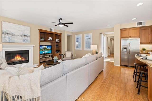 living room with ceiling fan and light hardwood / wood-style flooring