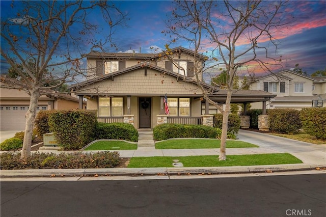 craftsman-style home with driveway, covered porch, stone siding, and stucco siding