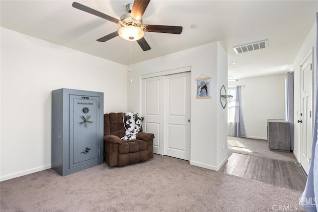 living area with ceiling fan and carpet