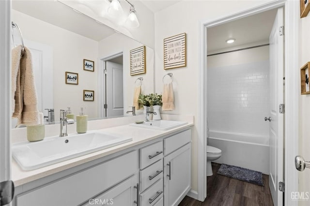 full bathroom with toilet, tiled shower / bath, wood-type flooring, and vanity