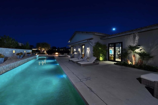 pool at twilight with a patio area