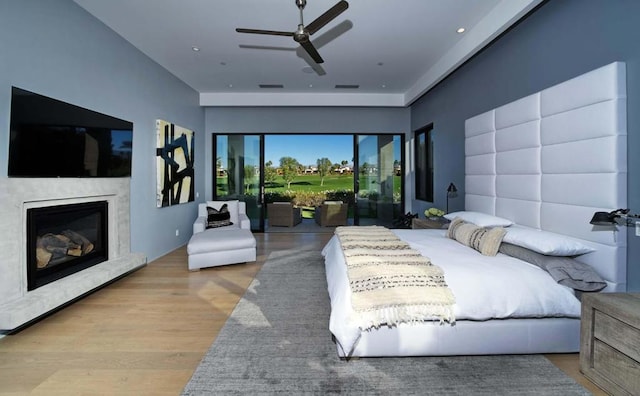 bedroom featuring access to outside, a fireplace, ceiling fan, and light hardwood / wood-style floors