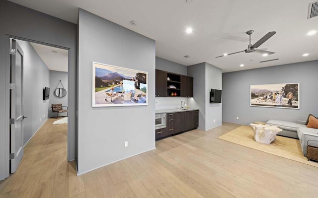 living room with ceiling fan, light hardwood / wood-style flooring, and sink