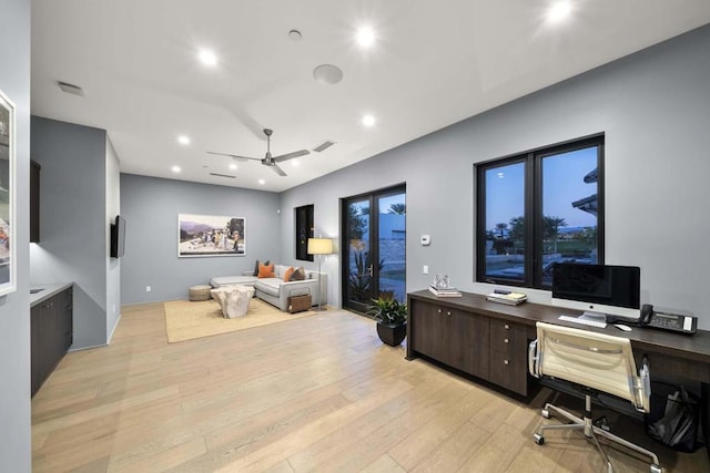 office with light wood-type flooring and ceiling fan