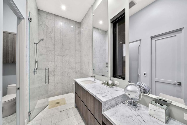 bathroom with a shower with shower door, vanity, and toilet