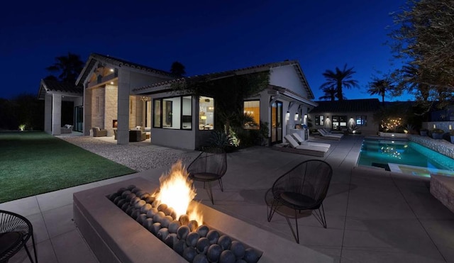 back house at twilight with a patio, an outdoor fire pit, and an outdoor structure