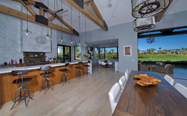 dining space featuring indoor bar, high vaulted ceiling, and beam ceiling