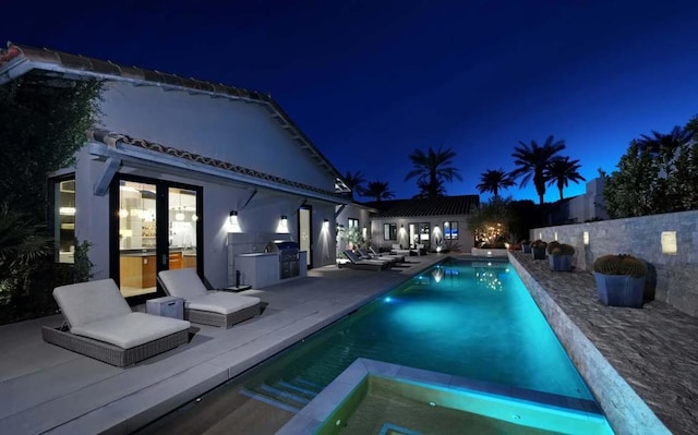 pool at twilight with an outbuilding, exterior kitchen, and a patio area