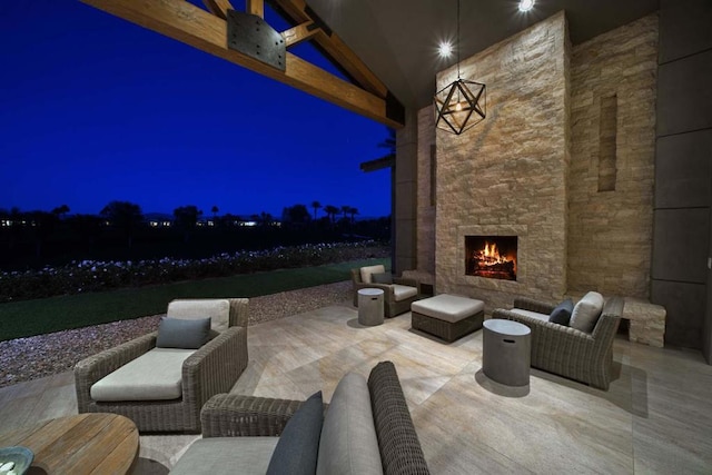 patio at night featuring an outdoor living space with a fireplace