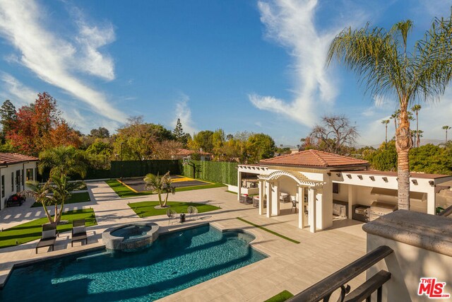 view of pool with a bar, a patio, an outdoor kitchen, and an in ground hot tub