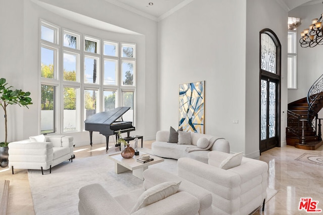 living room with a high ceiling, an inviting chandelier, and ornamental molding