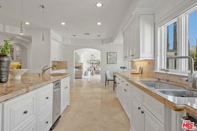 kitchen featuring sink, decorative light fixtures, white cabinetry, and light stone countertops