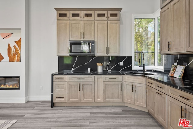 kitchen with tasteful backsplash, light wood-type flooring, a healthy amount of sunlight, and sink