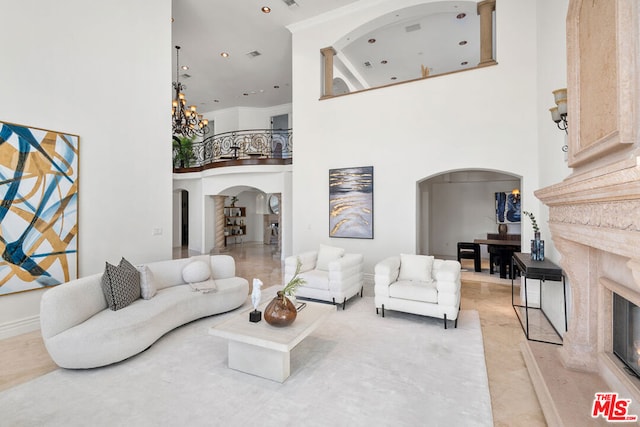 living room with a high end fireplace, a high ceiling, and a notable chandelier