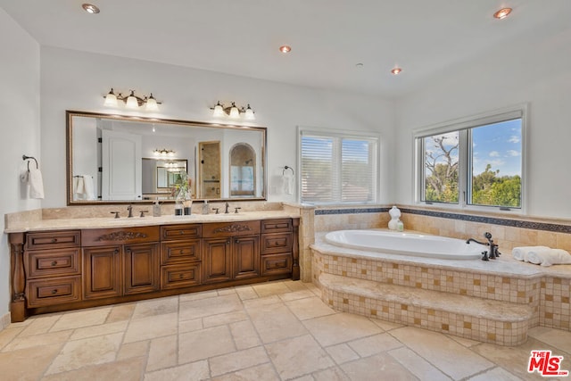 bathroom featuring a relaxing tiled tub and vanity